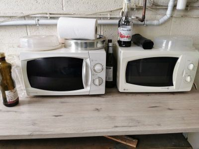 two microwaves that are sitting on a table next to each other