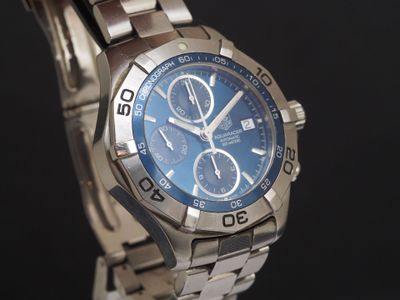 une montre en argent avec un cadran bleu sur fond noir