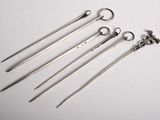 five pairs of surgical instruments are lined up on a white surface