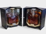 two bottles of whiskey in a black box on a white surface