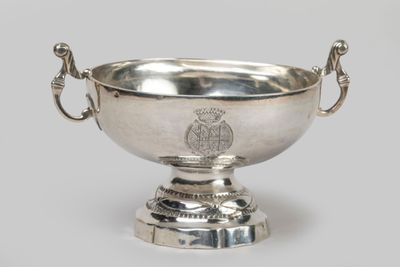 a silver bowl with a handle on a pedestal