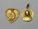 un gros plan sur deux pendentifs dorés en forme de cœur posés sur une surface blanche