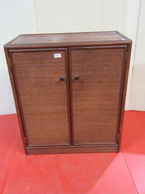 a brown cabinet sitting on a red floor next to a white wall