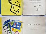 trois livres ouverts, ornés de dessins, posés sur une surface bleue