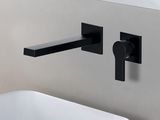 Le robinet noir est fixé au mur à côté d'un lavabo blanc.