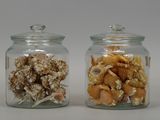 two glass jars with shells in them sitting on a table
