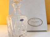 a glass bottle sitting on a table next to a box