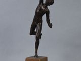 bronze statue of a man holding a tennis racquet on a wooden base