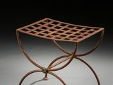 un petit tabouret en métal orné d'un motif en treillis