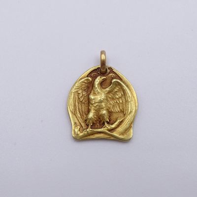 a close up of a gold pendant with an eagle on it