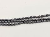 un gros plan d'un collier de perles noires posé sur une surface blanche