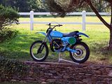 a blue dirt bike parked in front of a white fence