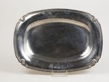 an antique silver plate on a stand on a white surface