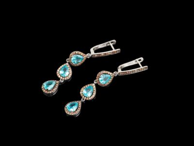 une paire de boucles d'oreilles en turquoise et diamants sur fond noir