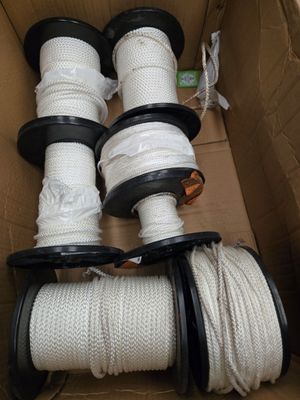 plusieurs rouleaux de corde blanche dans une boîte en carton munie de poignées noires