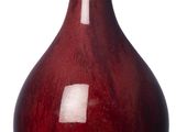 un vase rouge posé sur une surface blanche