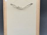 framed picture of a piece of art with a metal handle on a gray background