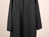 un manteau noir suspendu à un cintre sur un mur blanc