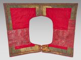 an old red and gold piece of cloth with a square shaped hole in the middle