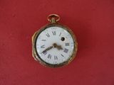 a small gold pocket watch with roman numerals on it
