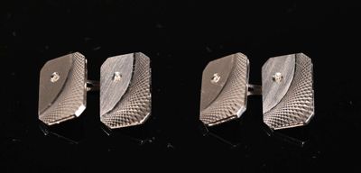 three silver cufflinks on a black surface with a black background