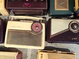 several old fashioned radio ' s are lined up on the floor