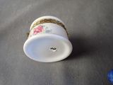 a small white cup with a gold rim sitting on a table