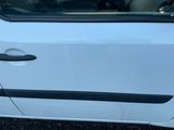 une voiture blanche aux finitions noires garée sur un parking