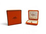une boîte orange contenant une bague, posée sur une surface blanche