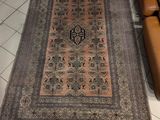 tapis posé sur le sol d'un salon où se trouvent un fauteuil et un canapé