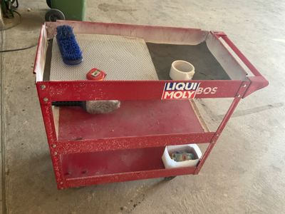a red cart with a bottle of liquid and a brush on it