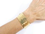 someone is wearing a gold bracelet with hexagons on it