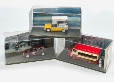 trois voitures miniatures dans une vitrine posée sur une table