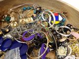 a wooden bowl filled with lots of jewelry on a table