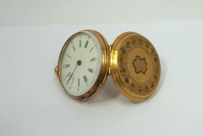 a gold pocket watch with roman numerals on it