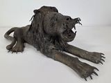 statue of a lion laying on its side with its mouth open