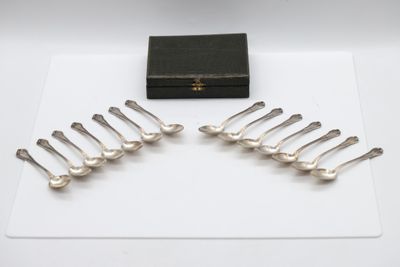 six silver spoons and a box on a white surface