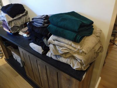 une photo montrant une pile de vêtements posée sur un banc en bois