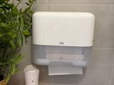 a toilet paper dispenser in the corner of a bathroom