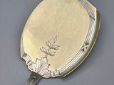 a silver mirror with flowers on it on a table