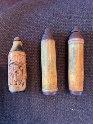 trois bouteilles en bois ornées de sculptures, posées sur une table