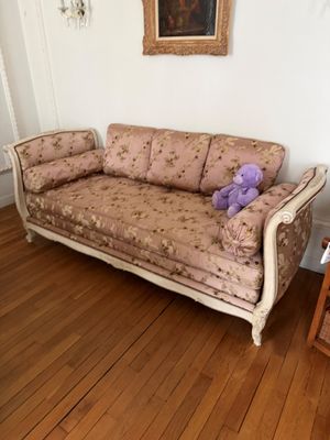 un ours en peluche violet assis sur un canapé dans un salon
