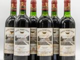 six bottles of wine are lined up on a white surface