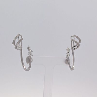une paire de boucles d'oreilles créoles en diamant posées sur un présentoir transparent