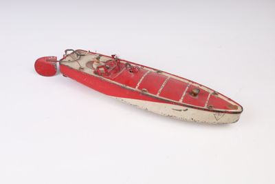 un petit bateau rouge posé sur une surface blanche