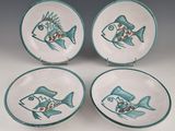 three plates with fish designs on them sitting on a table