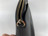 a hand holding a black purse with a gold zipper