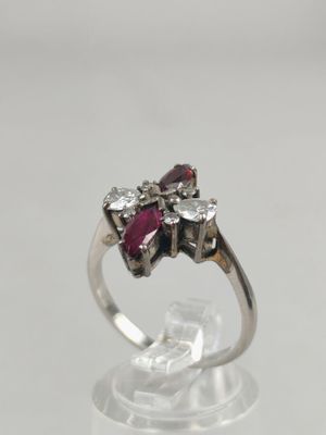 a close up of a diamond and ruby ring on a clear surface