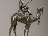 bronze statue of a man riding a camel with a spear in his hand
