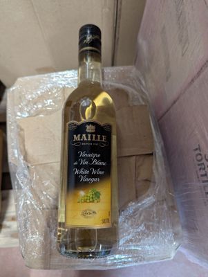 une bouteille d'huile d'olive dans une boîte posée par terre